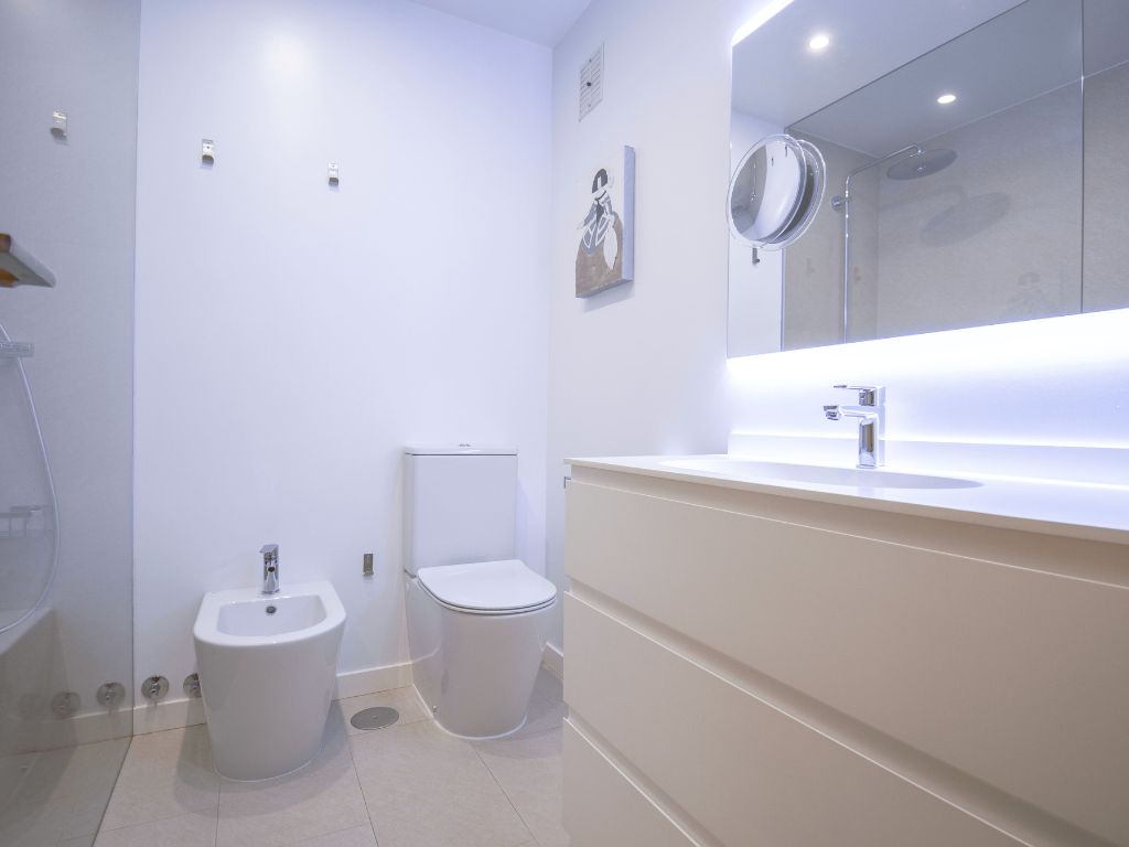 Foto desde la puerta del cuarto de baño en el que se observa uno de los lavabos suspendidos dentro del estilo Minimalista escogido.